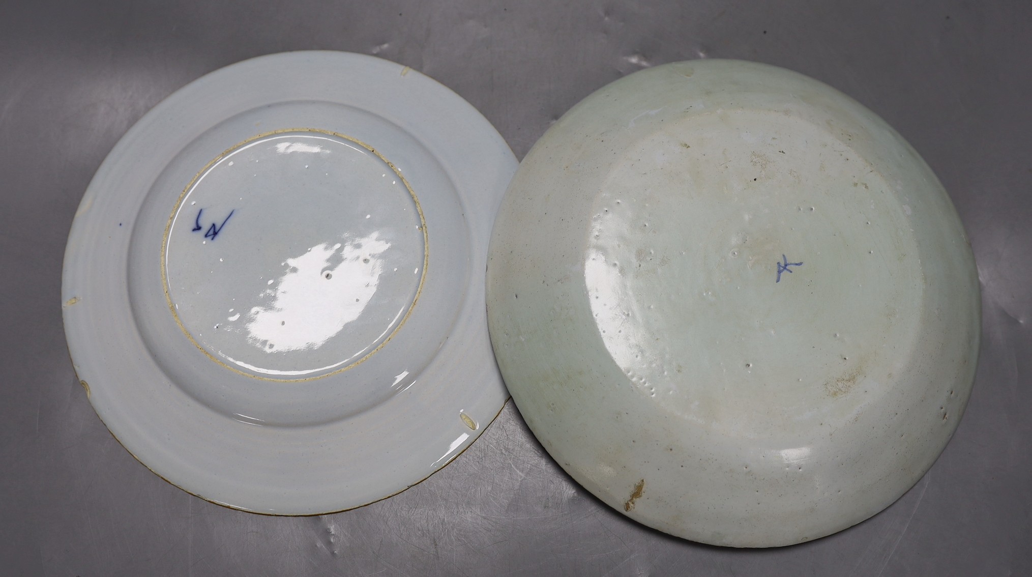 An early 18th century Delft polychrome dish and a mid 18th century Delft blue and white plate, largest 23.5cm diameter